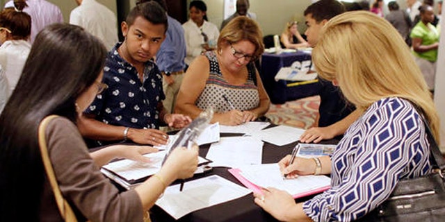 FILE - In this July 19, 2016, file photo, people fill out job applications at a job fair in Miami Lakes, Fla. Tepid income growth and shrinking opportunities for blue-collar workers have kept many Americans anxious about jobs and the economy, seven years after the Great Recession ended. The unemployment rate has fallen to a relatively low 4.9 percent. But many Americans are struggling to keep up with an economy that has been fundamentally transformed since the recession, and is very different from the one their parents experienced. (AP Photo/Lynne Sladky, File)