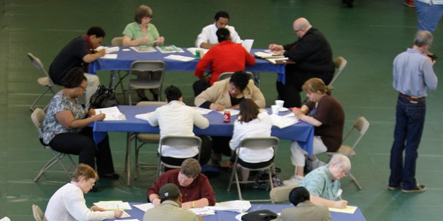 FILE: In this May 25, 2011, photo, people fill out job applications at the Jobapalooza job fair at Lake Erie College, in Painesville, Ohio.