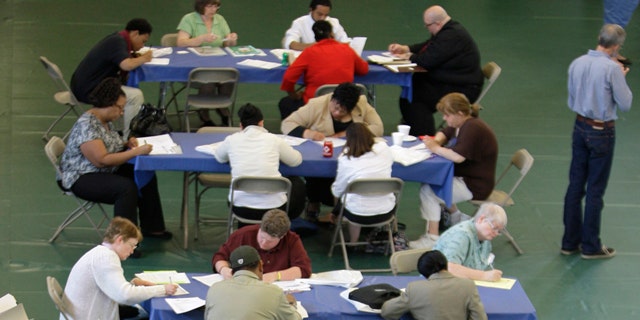 FILE: In this May 25, 2011, photo, people fill out job applications at the Jobapalooza job fair at Lake Erie College, in Painesville, Ohio.