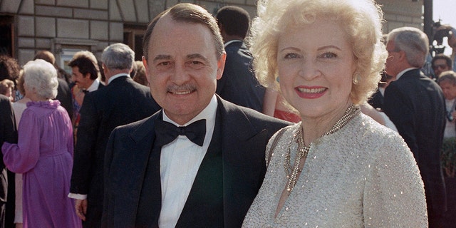 FILE- This Sept. 22, 1985, file photo shows John Hillerman, left, and Betty White, right, arriving at Emmy Awards in Pasadena, Calif. A spokeswoman for the family of Hillerman says the co-star of TVâs âMagnum, P.I.â has died. Hillerman was 84. Spokeswoman Lori De Waal said Hillerman died Thursday at his home in Houston. She said the cause of death has yet to be determined. (AP Photo/LIU, File)
