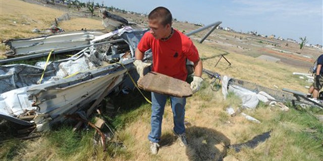 A boyscout volunteers to clean up debris from the tornado on a high school sports field.