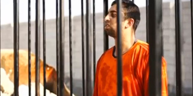 Muath Al-Kasaesbeh is seen standing in a cage.