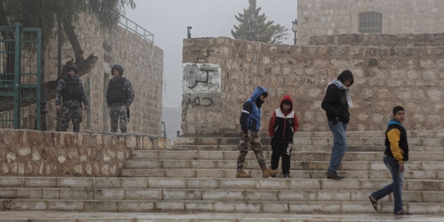 Jordanian security forces guard an entrance, left, as boys walk past in the morning mist in front of Karak Castle in the central town of Karak, about 140 kilometers (87 miles) south of the capital Amman, in Jordan Monday, Dec. 19, 2016. Gunmen assaulted Jordanian police in a series of attacks Sunday, including at the Karak Crusader castle popular with tourists, killing seven officers, two local civilians and a woman visiting from Canada, officials said. (AP Photo/Ben Curtis)