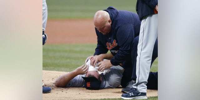 Detroit Tigers starting pitcher Jordan Zimmermann is tended to by head athletic trainer Doug Teter after getting hit by a ball off the bat of Cleveland Indians' Jason Kipnis during the first inning in a baseball game Wednesday, April 11, 2018, in Cleveland.