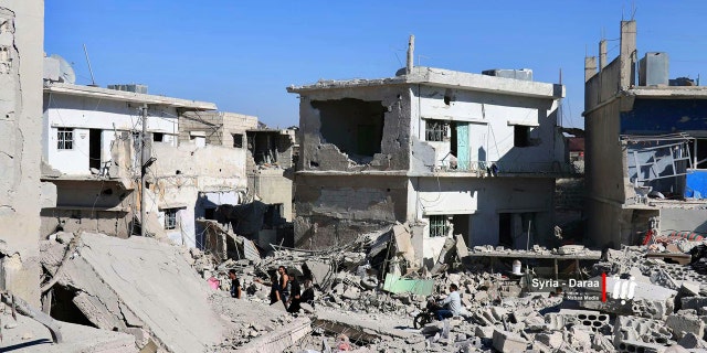 This Tuesday, June 26, 2018 photo provided by Nabaa Media, a Syrian opposition media outlet, shows civilians inspecting damaged buildings that were hit by Syrian government forces bombardment, in Daraa, southern Syria.