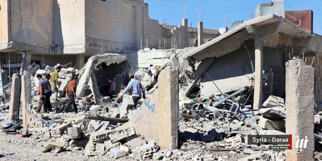 This Tuesday, June 26, 2018 photo provided by Nabaa Media, a Syrian opposition media outlet, shows civil defense workers and civilians inspecting damaged buildings that were hit by Syrian government forces bombardment, in Daraa, southern Syria