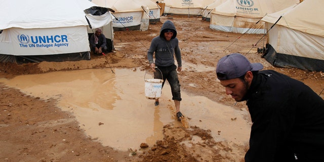Jan. 8, 2013: Syrian refugees work to clear water collected outside their tents after heavy rain at the Al-Zaatari refugee camp in the Jordanian city of Mafraq, near the border with Syria.