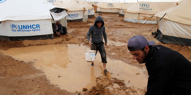 Jan. 8, 2013: Syrian refugees work to clear water collected outside their tents after heavy rain at the Al-Zaatari refugee camp in the Jordanian city of Mafraq, near the border with Syria.