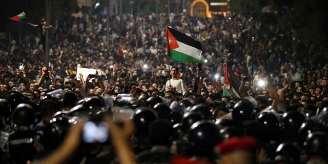 Jordanian protesters shout slogans and raise a national flag during a demonstration outside the Prime Minister's office in the capital Amman early Monday, June 4, 2018.