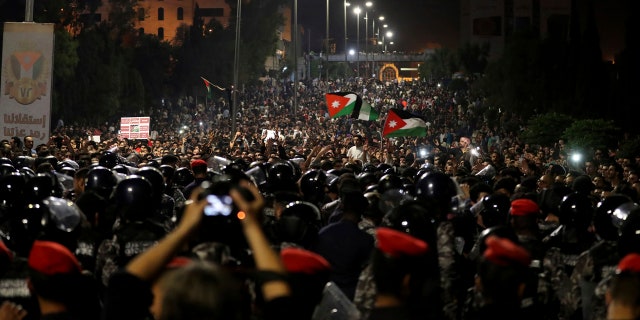 Jordanian protesters shout slogans and raise a national flag during a demonstration outside the Prime Minister's office in the capital Amman early Monday, June 4, 2018.