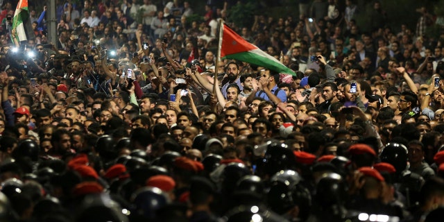 Jordanian protesters shout slogans and raise a national flag during a demonstration outside the Prime Minister's office in the capital Amman late early Monday, June 4, 2018.