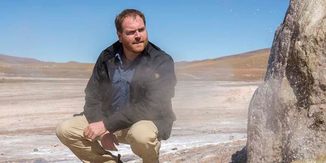Expedition Unknown host Josh Gates stands next to one of the 80 active geysers of El Tatio Geyser field in the Chilean Andes in the Atacama desert