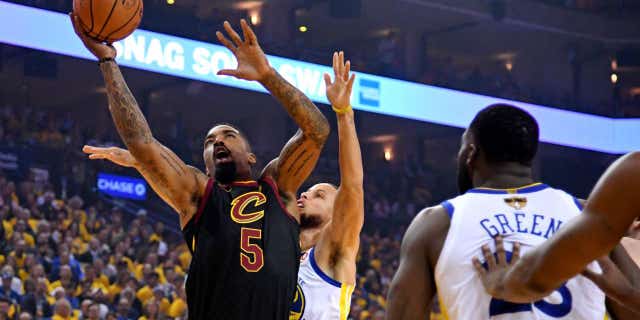 Cleveland's J.R. Smith, 5, handles the ball, surrounded by Golden State's Stephen Curry and Draymond Green.