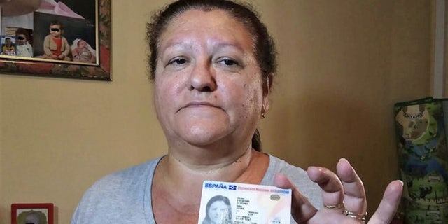 Juana Escudero, holding up her ID card, has a petition for a grave in Malaga, Spain be opened to prove that she is in fact alive.