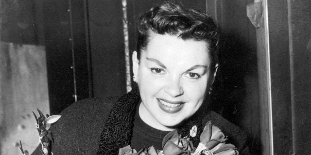 Judy Garland poses with long-stemmed roses in her arms as she arrives in New York City on Sept. 17, 1956. The singer-actress is to begin rehearsals for her Sept. 26 Palace Theater engagement. (AP Photo)