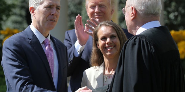 FILE: April 10, 2017: Judge Neil Gorsuch shakes hands with Supreme Court Associate Justice Anthony Kennedy after being sworn into the Supreme Court. He is accompanied by wife Louise Gorsuch and President Trump in the White House Rose Garden, Washington, D.C.