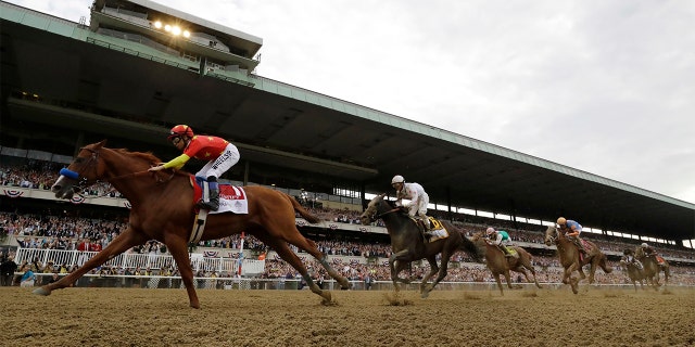 Justify (1), with jockey Mike Smith up, crosses the finish line to win the 150th running of the Belmont Stakes horse race and the Triple Crown on Saturday in Elmont, N.Y.
