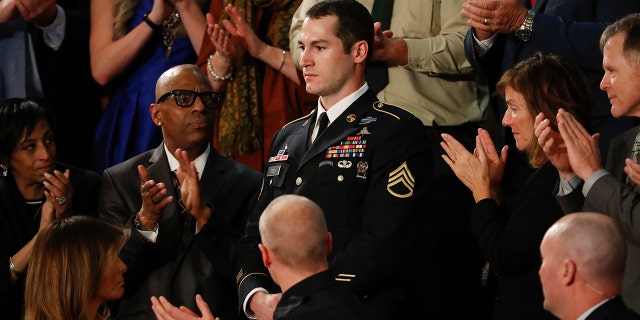 Army Staff Sgt. Justin Peck, center, stands as he's introduced by President Donald Trump during the State of the Union address to a joint session of Congress on Capitol Hill in Washington.