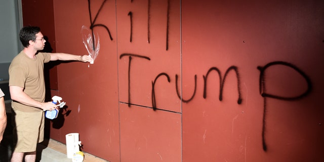 A man tries to remove "Kill Trump" graffiti as demonstrators riot in Oakland, California, U.S. following the election of Republican Donald Trump as President of the United States November 9, 2016.