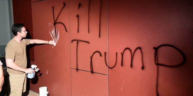 A man tries to remove "Kill Trump" graffiti as demonstrators riot in Oakland, California, U.S. following the election of Republican Donald Trump as President of the United States November 9, 2016.