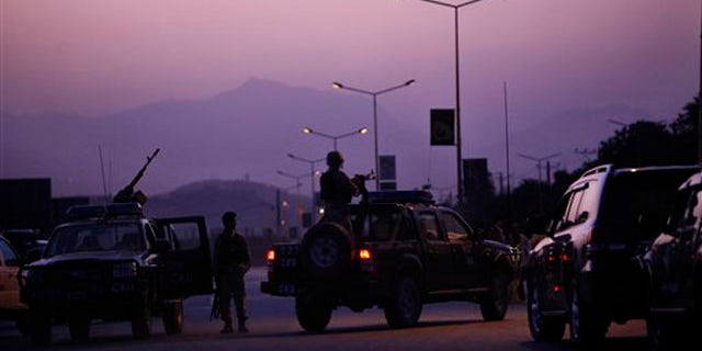 An Afghan army officer mans a heavy gun mounted to a vehicle at the entrance to the InterContinental hotel, which came under attack in Kabul, Afghanistan, June 29.