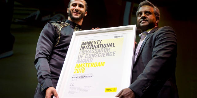 Former NFL quarterback and social justice activist Colin Kaepernick receives the Amnesty International Ambassador of Conscience Award for 2018 from Amnesty International Secretary General Salil Shetty, right, in Amsterdam, April 21, 2018.