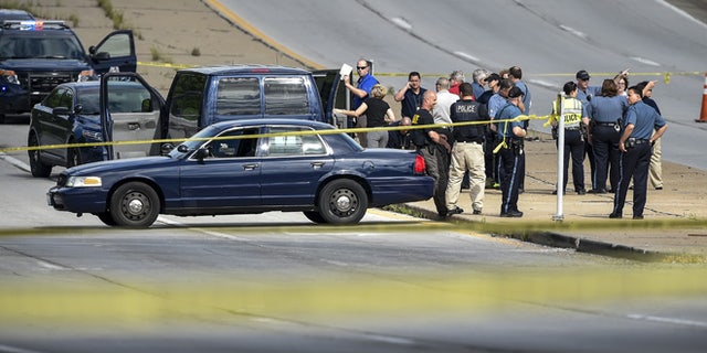 Authorities talk after they closed both directions of Bannister Road along with both directions of Highway 71 in their investigation of a carjacking and shooting suspect arrest Monday, May 9, 2016, in Kansas City, Mo. (David Eulitt /The Kansas City Star via AP) MANDATORY CREDIT