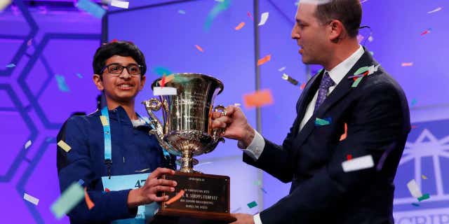 Karthik Nemmani, 14, from McKinney, Texas, holds the Scripps National Spelling Bee Championship Trophy with Scripps President and Chief Executive Officer Adam Symson after winning the Scripps National Spelling Bee in Oxon Hill, Md., May 31, 2018.