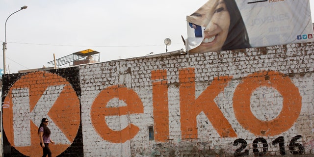A woman walks past a mural promoting presidential candidate Keiko Fujimori in the Villa el Salvador district of Lima, Peru, Saturday, June 4, 2016. The South American country is gearing up for a tight June 5th runoff between Keiko Fujimori, the daughter of jailed former President Alberto Fujimori, and former World Bank economist Pedro Kuczynski. (AP Photo/Rodrigo Abd)
