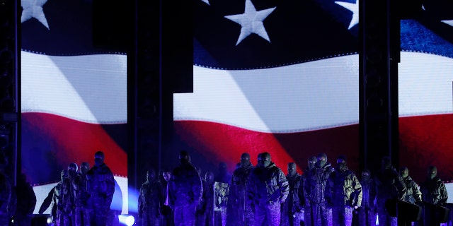 Kendrick Lamar (left, rear, in white shirt) performs a medley in front of an American flag at the 60th Annual Grammy Awards on Jan. 28, 2018.