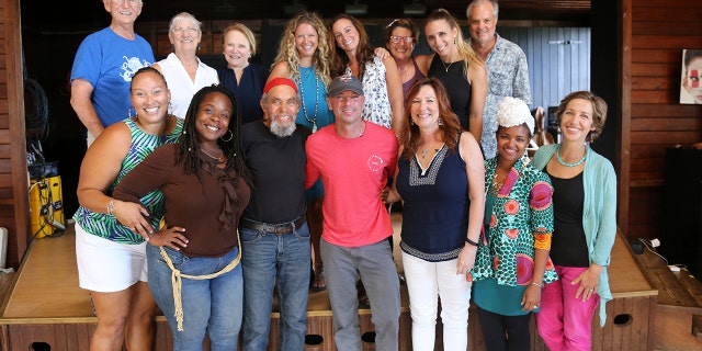 In this Feb. 28, 2018 photo provided by Jill Trunnell, country singer Kenny Chesney, foreground center, poses with residents, background from left, Jim Furneaux, Carol Furneaux, Glenda Werbel, Angela Warren, Jenna Fox, Jude Woodcock, Jillian Grossman and Bill Stelzer, and foreground from left, Audrey Penn, Ingrid Smith, Eddie Bruce, Chesney, Kim Wild, Jeune Provost and Lauren Magnie at St. John School of the Arts in St. John, U.S. Virgin Islands.