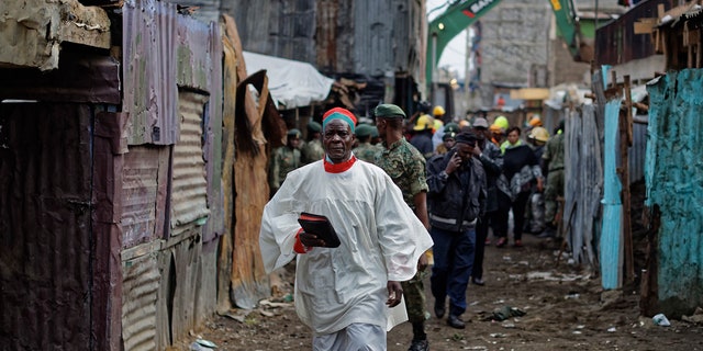 A priest holding a bible walks past the scene of a five-storey collapsed building in the Huruma neighborhood of Nairobi, Kenya, June 3, 2018.