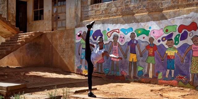 Kenyan ballet dancer Joel Kioko, 16, strikes a pose as a joke as he walks through the courtyard of a school where he was teaching young dancers in Nairobi, Kenya.