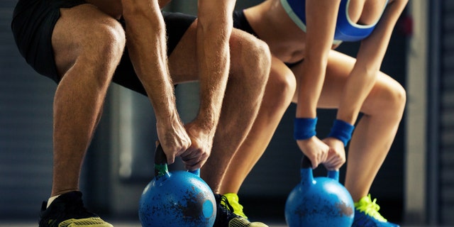 Fit man and woman training by kettlebell.