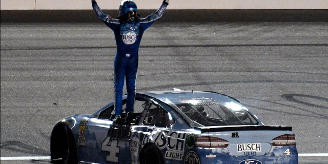 Kevin Harvick stands on his car as he celebrates his win in the NASCAR Cup Series auto race at Kansas Speedway on Saturday, May 12, 2018, in Kansas City, Kan.
