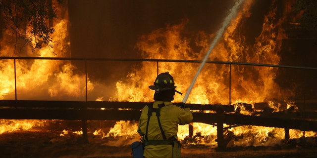 FILE - In this Oct. 9, 2017 file photo, a firefighter sprays a hose into a Keysight Technologies building in Santa Rosa, Calif. The Santa Rosa Press Democrat reported that more than 100 boxes of letters and other materials from tech pioneers William Hewlett and David Packard burned in the fires. Electronics firm Keysight Technologies had acquired the archives through spinoffs, and the archives were stored at its offices in Santa Rosa. (AP Photo/Jeff Chiu, file)