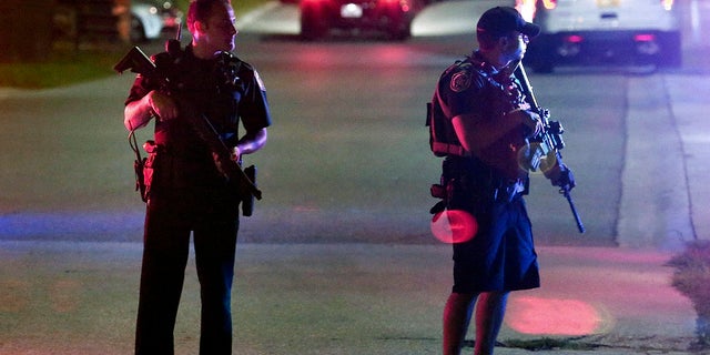 Two law enforcement officers stand guard outside Osceola Regional Medical Center after two Kissimmee police officers were shot Friday, Aug. 18, 2017, in Kissimmee, Fla.