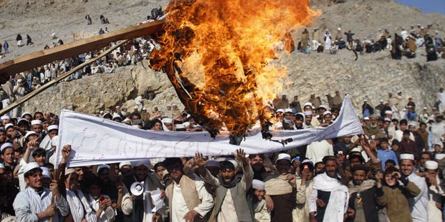 In this Feb. 24, 2012 file photo, Afghans burn an effigy representing U.S. President Barack Obama during an anti-U.S. protest in Ghani Khail, east of Kabul, Afghanistan.