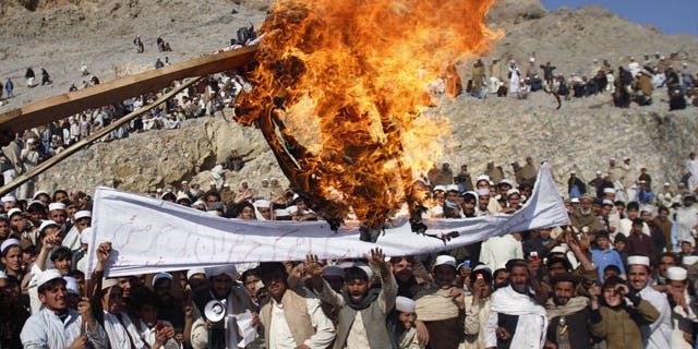 In this Feb. 24, 2012 file photo, Afghans burn an effigy representing U.S. President Barack Obama during an anti-U.S. protest in Ghani Khail, east of Kabul, Afghanistan.