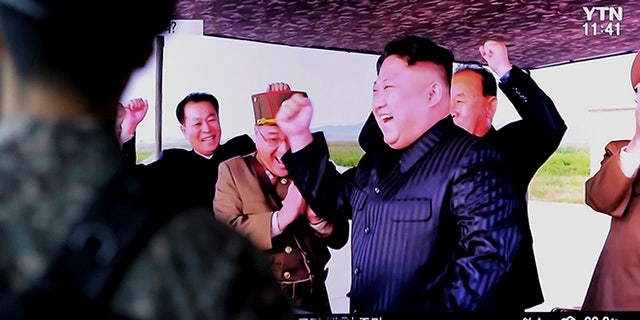 North Korean leader Kim Jong Un, center, celebrates the test launch Friday of an intermediate range Hwasong-12 missile at an undisclosed location in North Korea