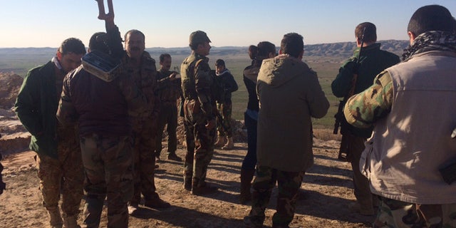Kurdish forces stand near Kirkuk, staring off at the ISIS front on the horizon.