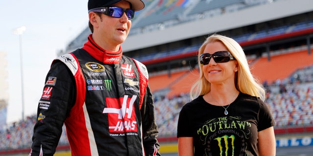 FILE - In this May 22, 2014, file photo, Kurt Busch, left, stands with Patricia Driscoll before qualifying for a NASCAR Sprint Cup series auto race at Charlotte Motor Speedway in Concord, N.C. Driscoll, the former girlfriend of Busch, has been charged with stealing from a military charity she led. She was indicted on two counts each of wire fraud, mail fraud, and tax evasion, and one count of attempts to interfere with administration of Internal Revenue laws. (AP Photo/Terry Renna, File)