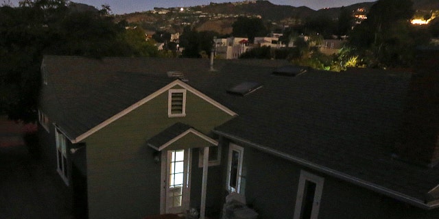 The Pacific Palisades area of Los Angeles at twilight is blacked out, the only light coming from a laptop computer screen in a home, foreground, and from a few others with backup power, as the Los Angeles Department of Water and Power said about 140,000 people are without electricity after the agency shut down a power station in the northeast San Fernando Valley that caught fire Saturday, July 8, 2017.