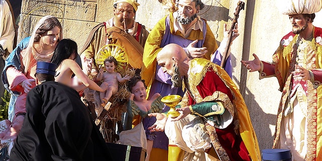 Vatican gendarmes attempt to block a topless activist of women's rights group Femen, who tries to reach the Nativity scene in Saint Peter's square in the Vatican.