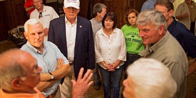 Republican presidential candidate Donald Trump, center, and his running mate, Indiana Gov. Mike Pence, listens to flood victims Jimmy and Olive Gordan during a tour of their flood damaged home.