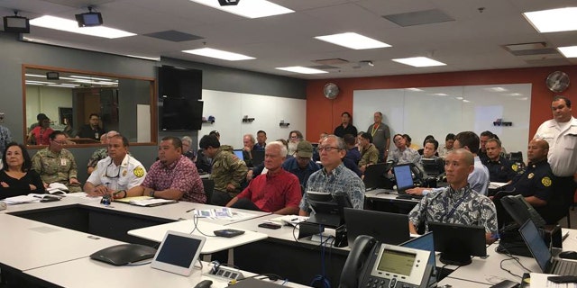 In this photo provided City and County of Honolulu, Mayor Kirk Caldwell, center, receives a briefing from the Central Pacific Hurricane Center on Hurricane Lane at the Emergency Operations Center in Honolulu, Tuesday, Aug. 21, 2018.