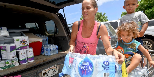 Brianna Sugimura unloads supplies for riding out the storm while her children, Radon-Kai and Kanaloa watch in the parking lot of a Walmart store Tuesday, Aug. 21, 2018, in Lihue, on the island of Kauai in Hawaii.