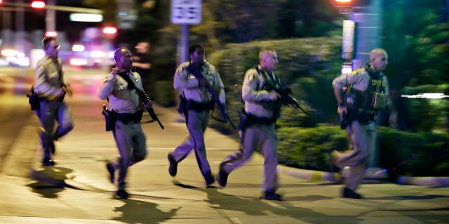 Police run to cover at the scene of a shooting near the Mandalay Bay resort and casino on the Las Vegas Strip, Sunday, Oct. 1, 2017, in Las Vegas. Multiple victims were being transported to hospitals after a shooting late Sunday at a music festival on the Las Vegas Strip.
