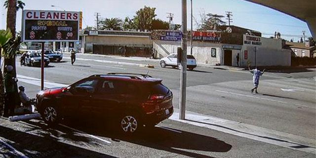 Dec. 12, 2015: In this image made from security video footage provided by the Los Angeles County Sheriff, a man, right, walks with a gun in his hand in Lynwood, Calif.