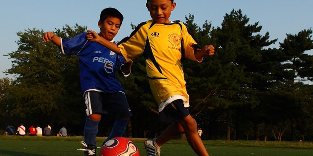 QUEENS, NY - SEPTEMBER 7: Boys play a pickup game of soccer as their adult relatives participate in the Fedeiguayas Soccer League on September 7, 2007 at Flushing Meadows Park in the Queens Borough of New York. A large Hispanic population from Mexico, Central and South America now living in New York congregate to this park every weekend to play soccer, and relax with family and friends. They play on ten soccer fields throughout the park and play goes from early morning till dusk. The participants are highly skilled semi pro level players and each team dresses in the colors of their country and play as if it was their own World Cup. Matches are very competitive as the pride of each team's country is on the line. (Photo by Al Bello/Getty Images)